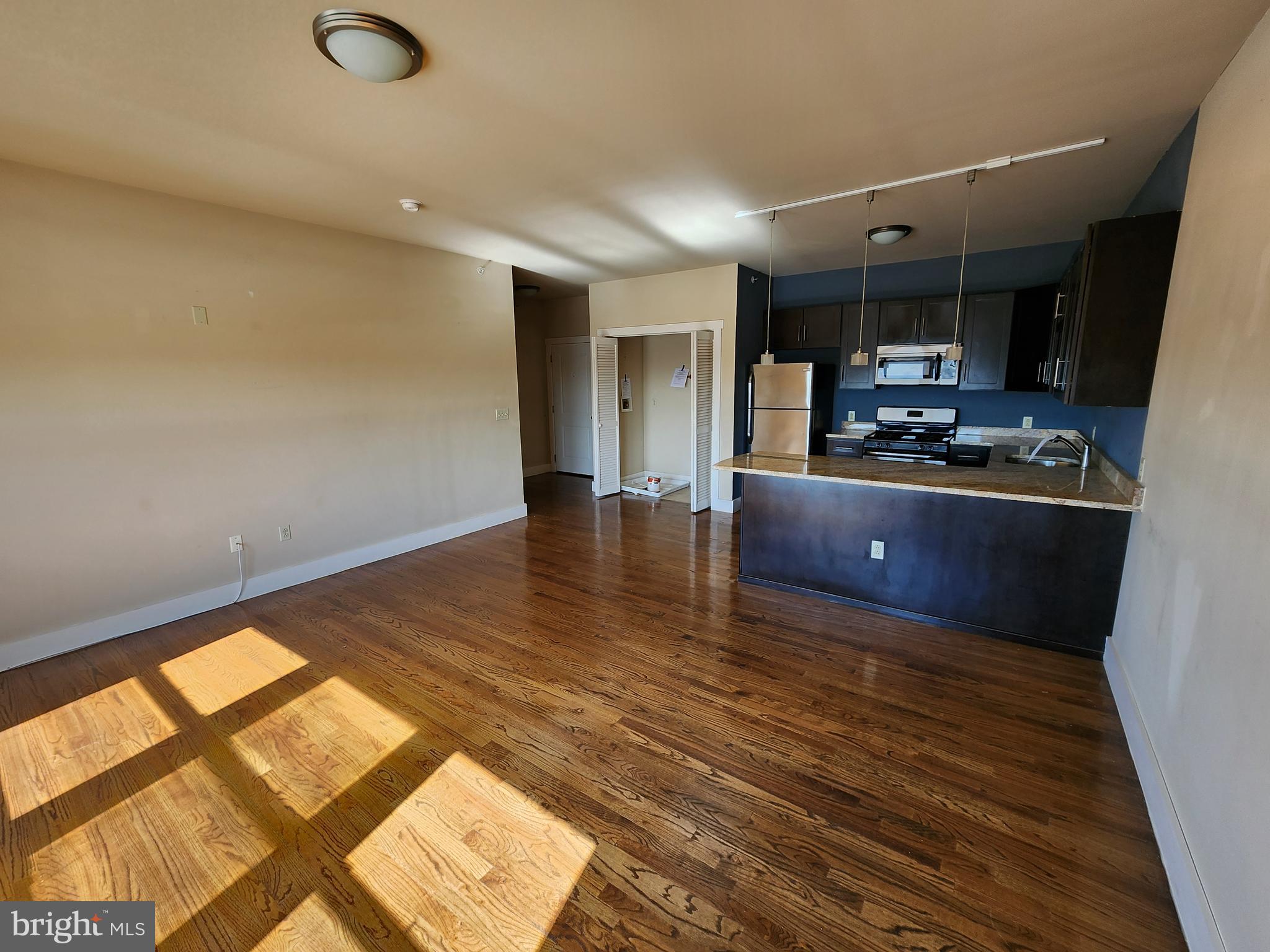 a living room with hard wood floors and a kitchen