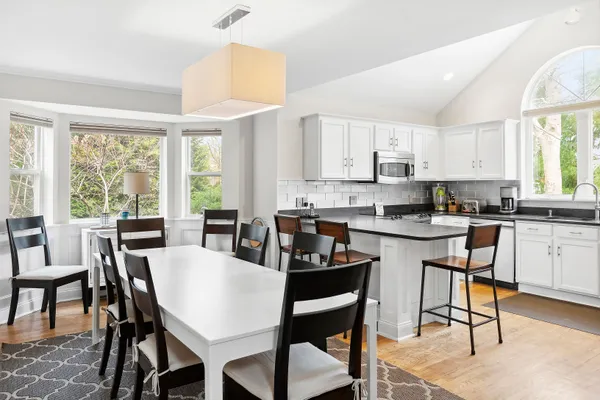 a kitchen with a dining table chairs and white appliances