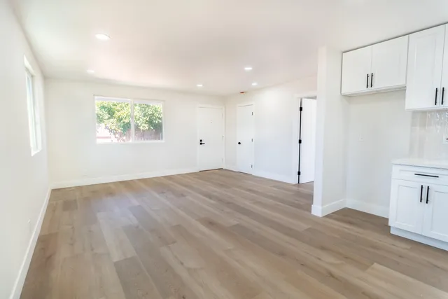 an empty room with wooden floor and windows