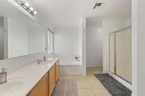 a spacious bathroom with a double vanity sink a mirror and a bathtub
