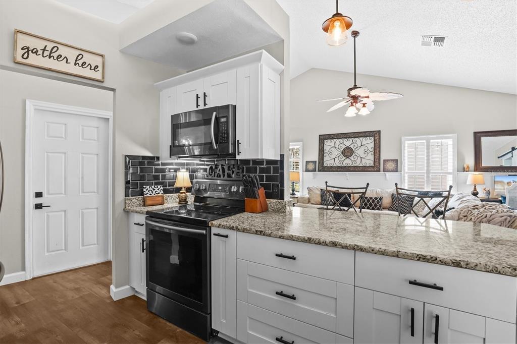 1049 Larkin Road Spring Hill, FL 34608 - Photo 23 of 64 a kitchen with granite countertop stainless steel appliances a sink stove and refrigerator