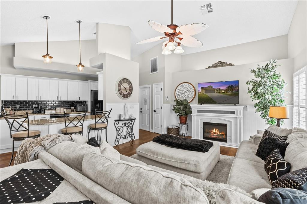 1049 Larkin Road Spring Hill, FL 34608 - Photo 28 of 64 a living room with furniture a fireplace kitchen view and a chandelier