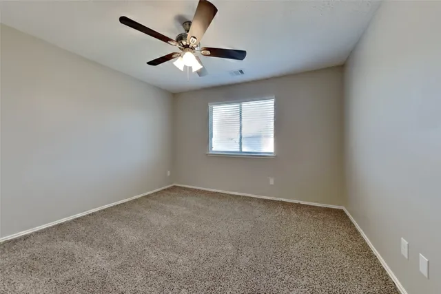 an empty room with a window and a fan