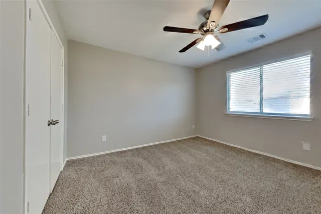 an empty room with windows and fan