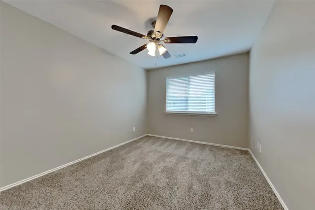 an empty room with a window and a fan