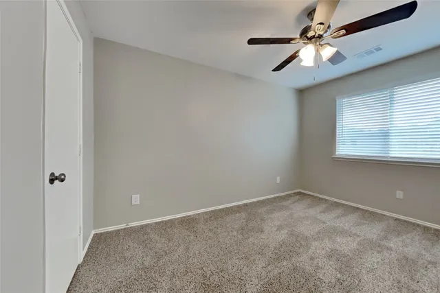 an empty room with a chandelier fan and windows