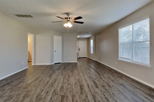 a view of an empty room with wooden floor and a window