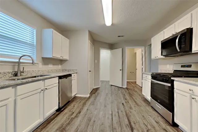 a kitchen with stainless steel appliances granite countertop a stove a sink and a microwave