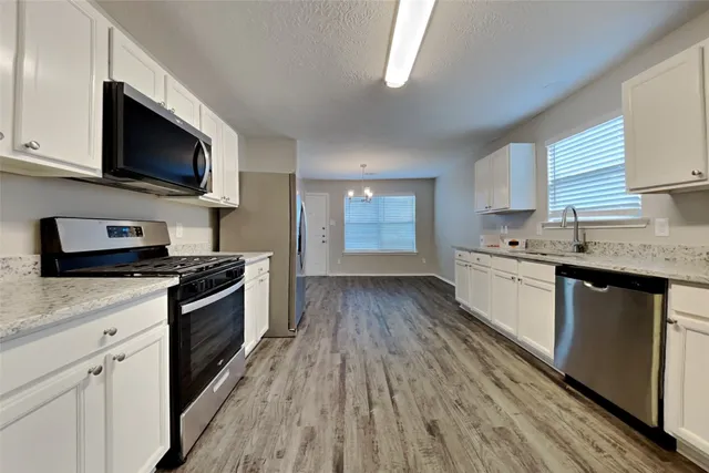 a kitchen with stainless steel appliances kitchen island granite countertop a stove a sink and a microwave