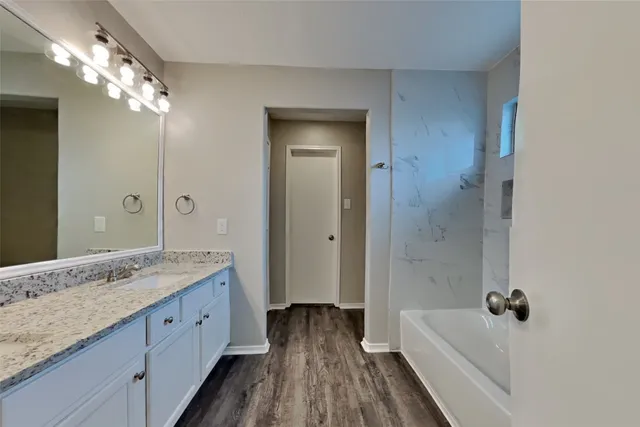 a bathroom with a granite countertop sink a large mirror and a bathtub