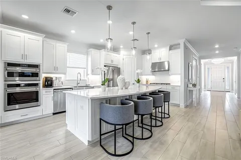 a kitchen with stainless steel appliances granite countertop a stove a sink a refrigerator and a dining table with wooden floor