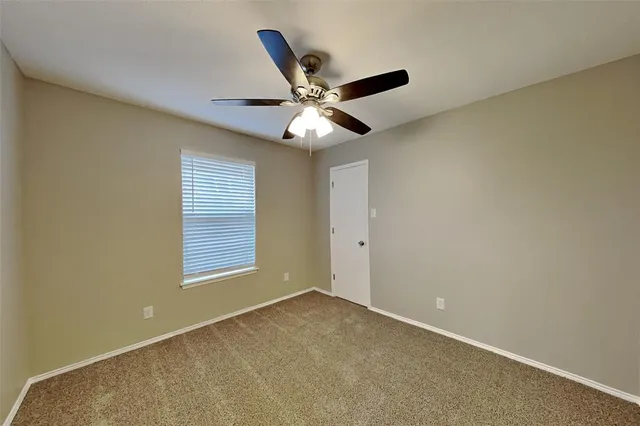 a view of an empty room with a ceiling fan and a window