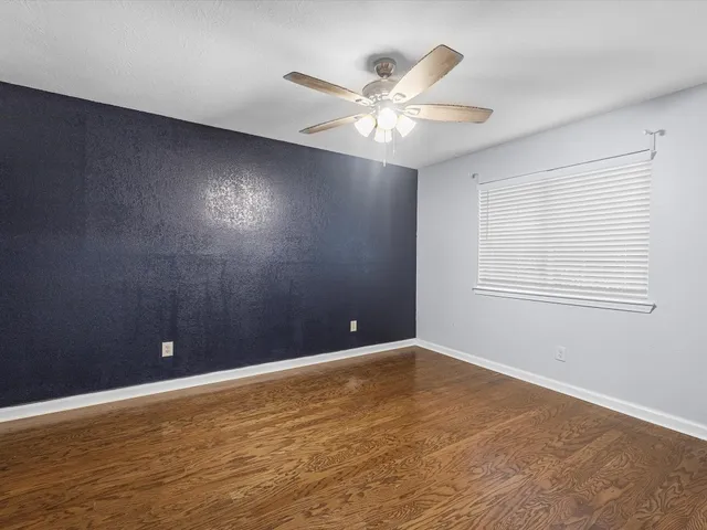 a view of an empty room with window and wooden floor