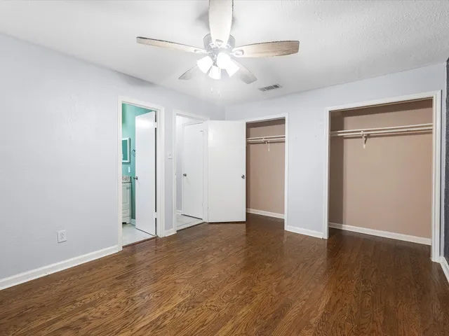 an empty room with wooden floor and ceiling fan