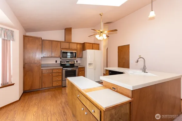 a kitchen with a sink a counter top space stainless steel appliances and cabinets