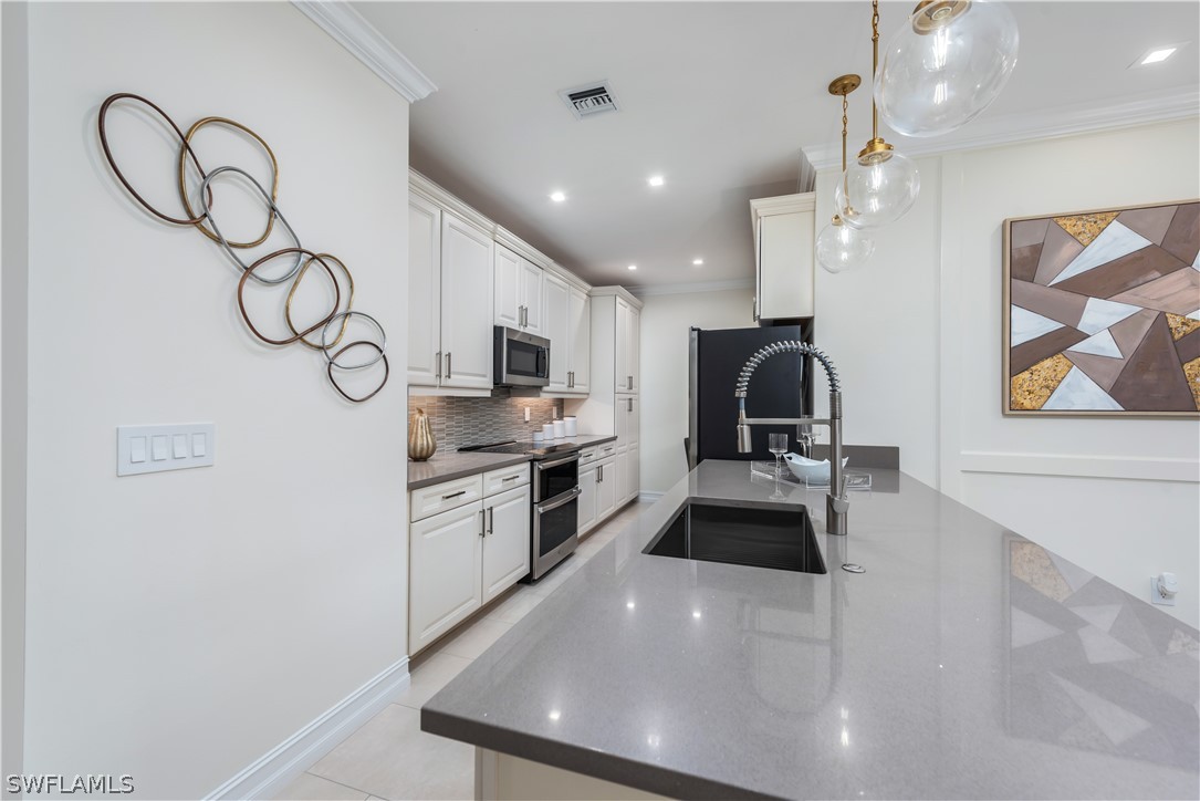 7341 Rockefeller Drive Naples, FL 34119 - Photo 15 of 34 a kitchen with stainless steel appliances kitchen island a refrigerator and a stove top oven