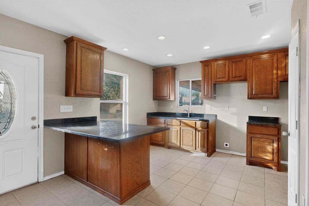 1121 Reedsport Place DeSoto, TX 75115 - Photo 34 of 40 a kitchen with kitchen island granite countertop a stove sink and cabinets