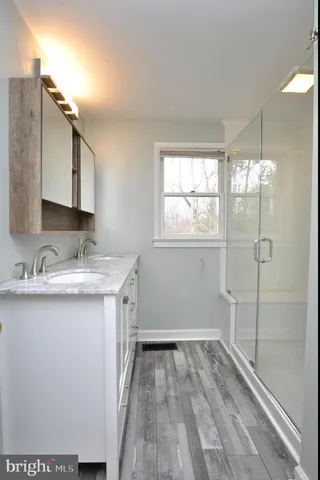 a bathroom with a granite countertop sink a mirror and a shower