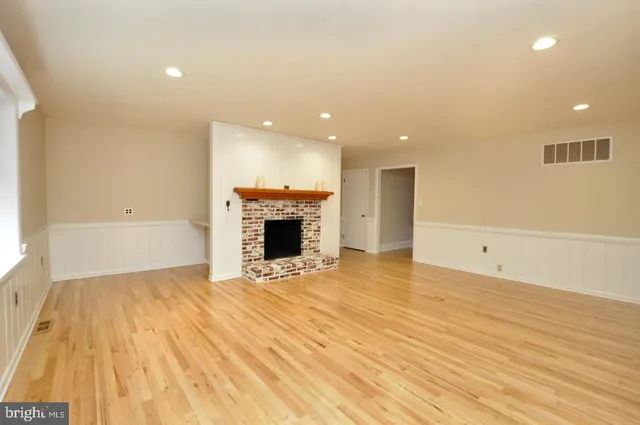 a view of empty room with wooden floor and fireplace