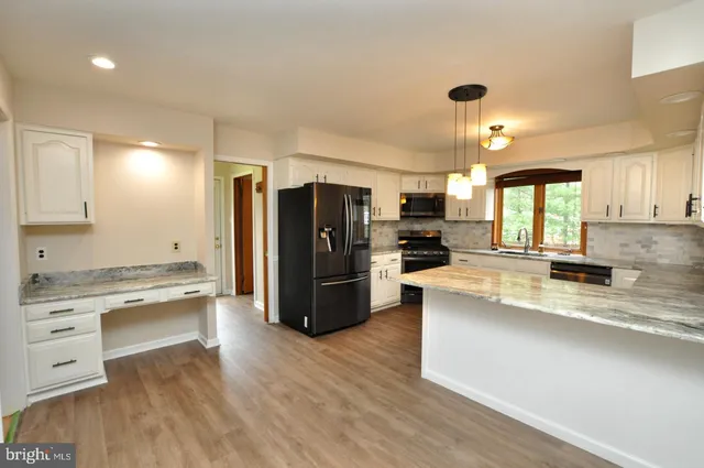 a large kitchen with stainless steel appliances kitchen island a large counter top and a wooden floors