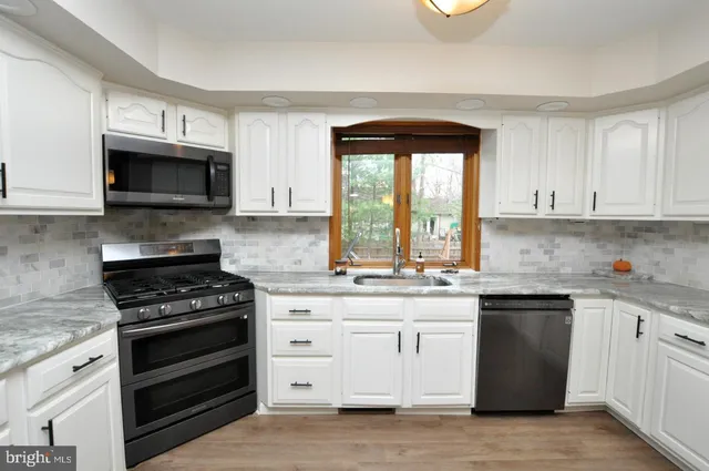 a kitchen with granite countertop a stove a microwave a sink and cabinets