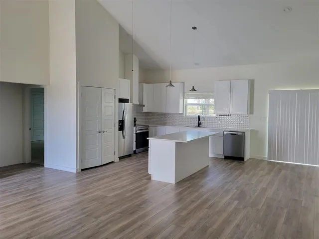 a kitchen with stainless steel appliances a sink a stove a refrigerator cabinets and wooden floor