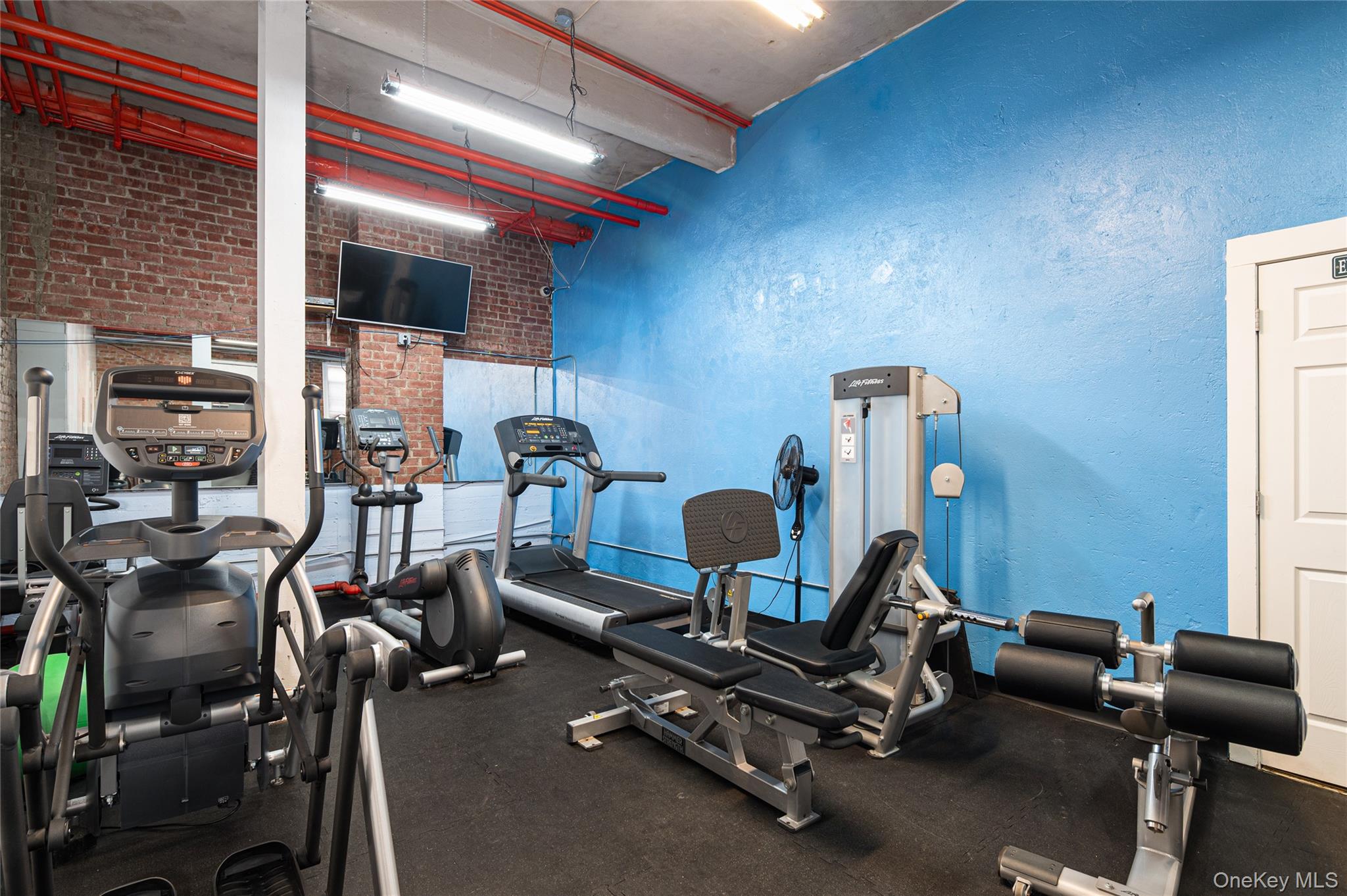 633 Old Post Road, Unit 23 Bedford, NY 10506 - Photo 6 of 10 Exercise room featuring brick wall and a high ceiling