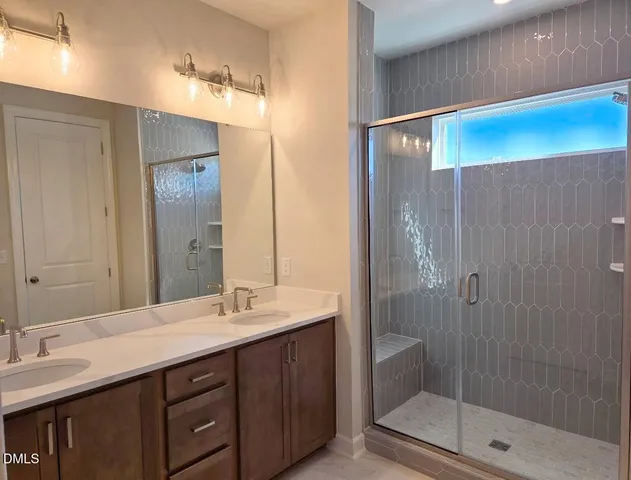 a bathroom with a double vanity sink mirror and shower