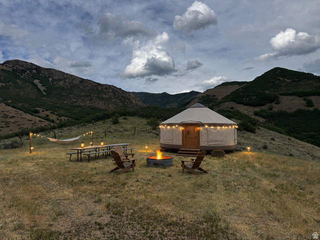 123 West Spring Hollow Road Morgan, UT 84050 - Photo 4 of 13 Freestanding yurt structure with a wood entry door on a sloped, vegetated landscape