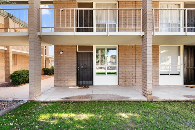 a view of a brick house with a yard and plants