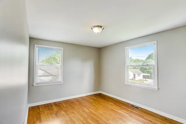 an empty room with wooden floor and window