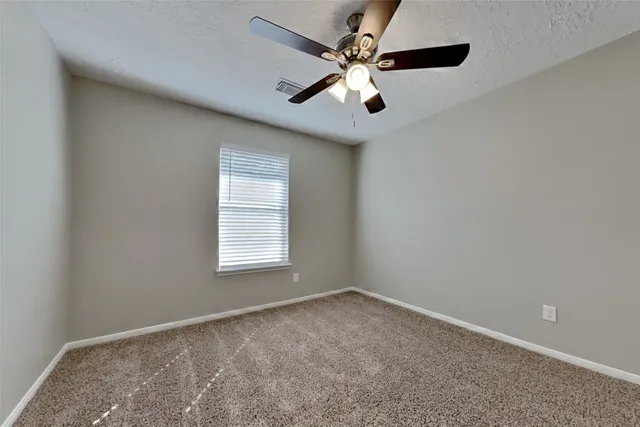 an empty room with a window and a fan