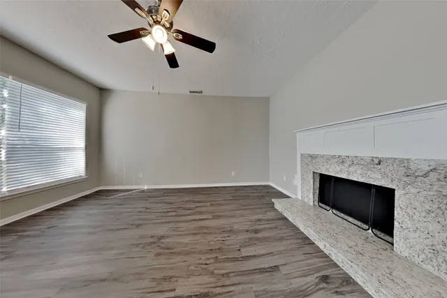 an empty room with fireplace fan and windows