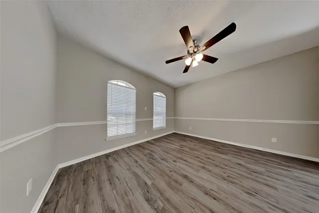 an empty room with wooden floor and windows