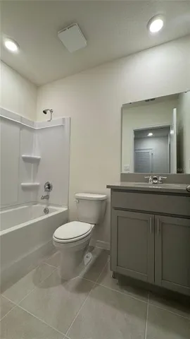 a bathroom with a granite countertop sink toilet a mirror and bathtub