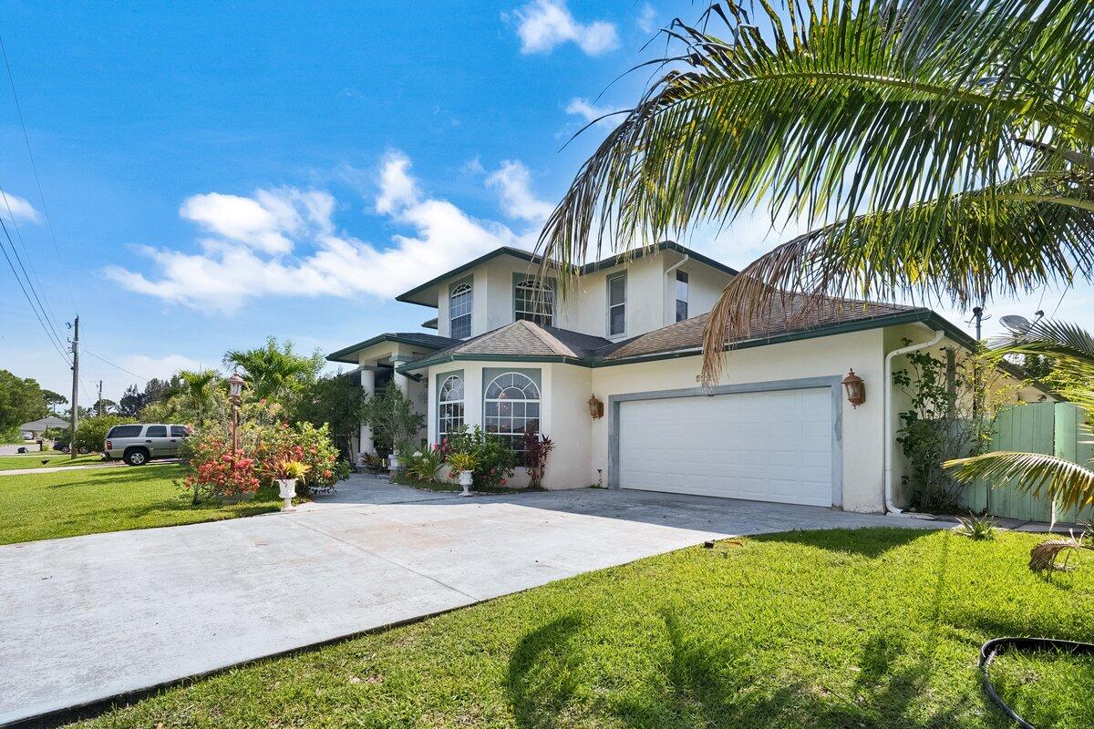 5221 Northwest Mayfield Lane Port St. Lucie, FL 34983 - Photo 1 of 34 a front view of a house with a garden and yard