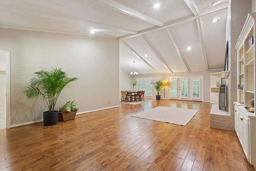 4108 Old Mill Road Waco, TX 76710 - Photo 7 of 39 Spacious open-concept living area featuring coffered ceiling with recessed lighting, hardwood flooring throughout, and a custom built-in cabinetry wall with shelving and fireplace