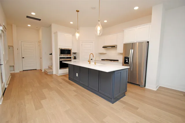 a kitchen with stainless steel appliances a sink a refrigerator a center island cabinets and wooden floor
