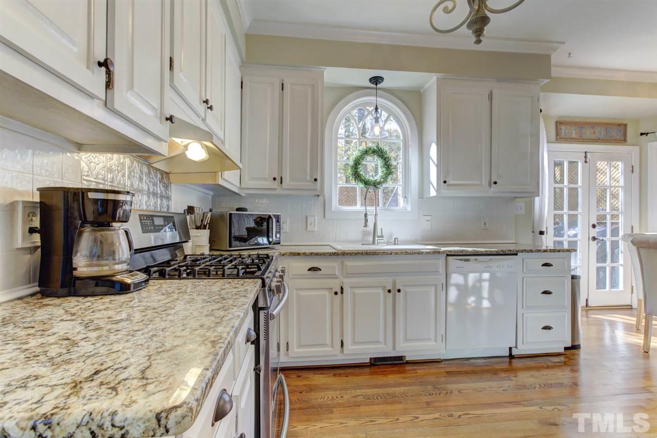 4417 Lancashire Drive Raleigh, NC 27613 - Photo 3 of 30 a kitchen with granite countertop a stove a sink and a wooden cabinets