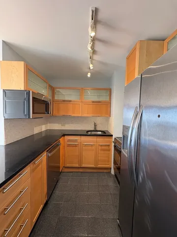 a large kitchen with stainless steel appliances granite countertop a refrigerator and a sink