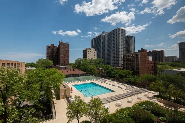 a view of a multi story residential apartment building with a yard and large trees