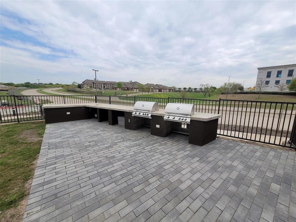2700 Old Denton Road, Unit 2238 Carrollton, TX 75007 - Photo 20 of 21 Expansive outdoor kitchen featuring two built-in grills, a large counter space, and integrated storage, all set on a durable paver patio