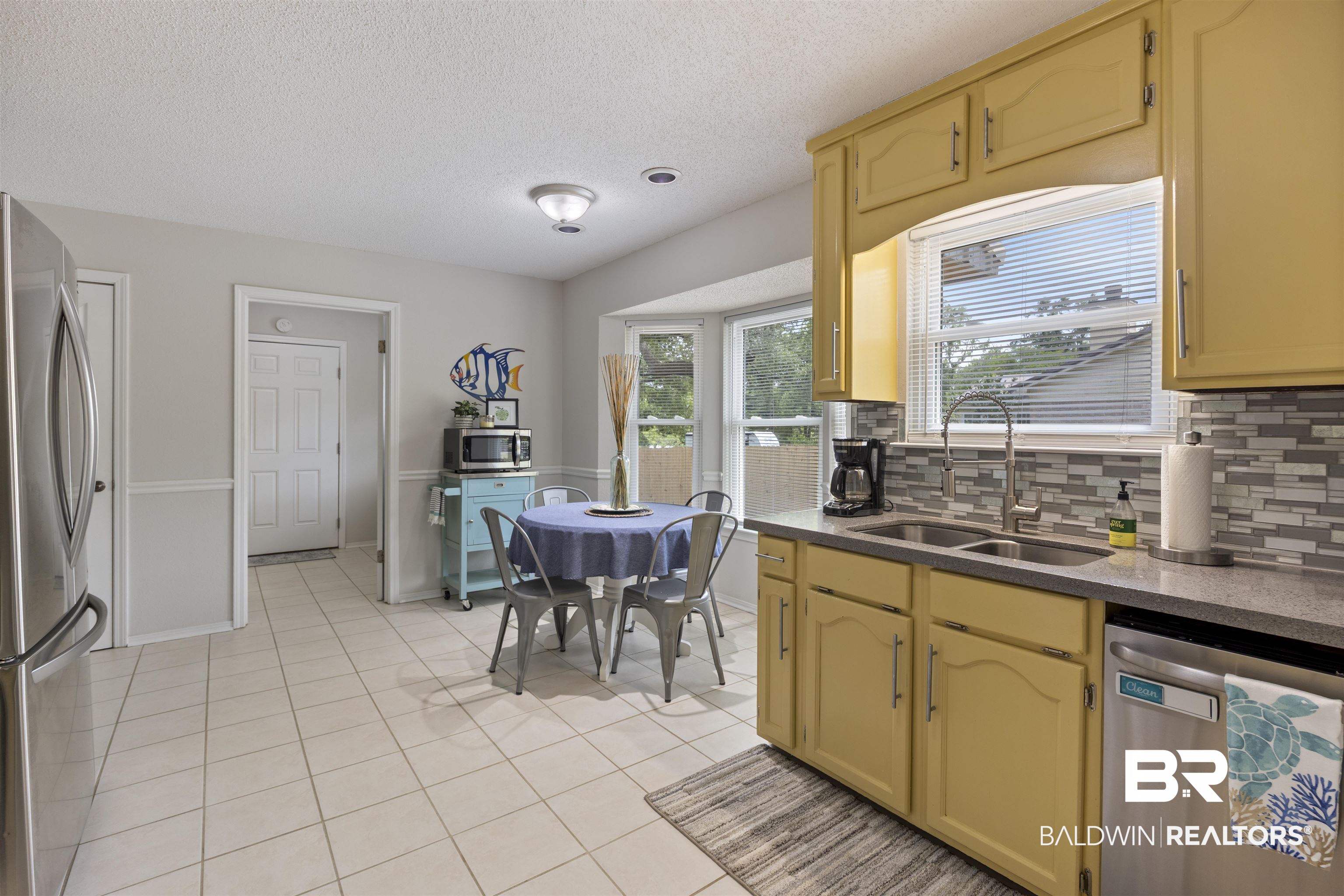 9771 Clarke Ridge Road Foley, AL 36535 - Photo 31 of 72 Kitchen with a sink, stainless steel appliances, a textured ceiling, backsplash, and light tile patterned flooring.