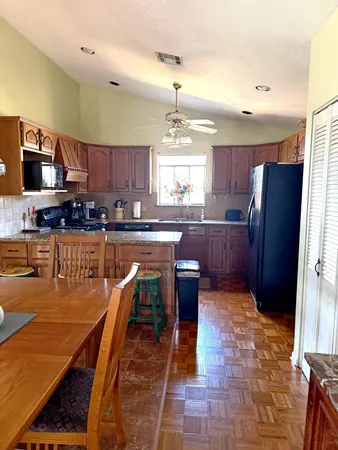 a kitchen with stainless steel appliances granite countertop a stove top oven a sink a dining table and chairs