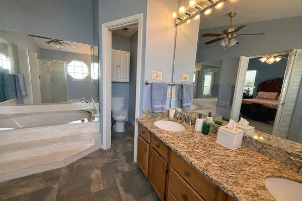 a bathroom with a granite countertop tub double vanity sink and a large mirror