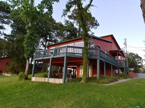 a view of house with a big yard and large trees