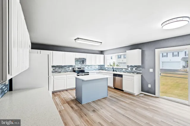 a kitchen with a refrigerator and white cabinets