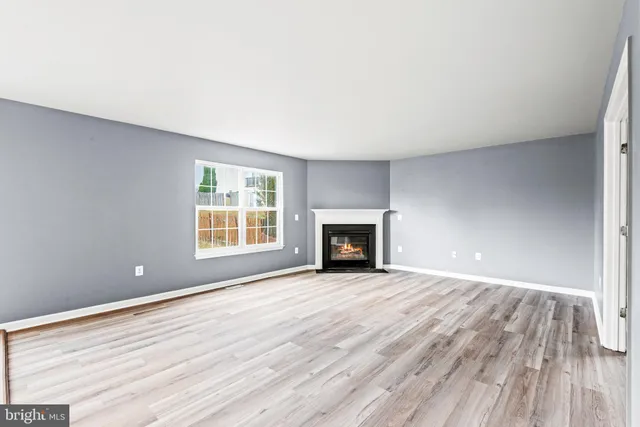 a view of empty room with wooden floor and fireplace