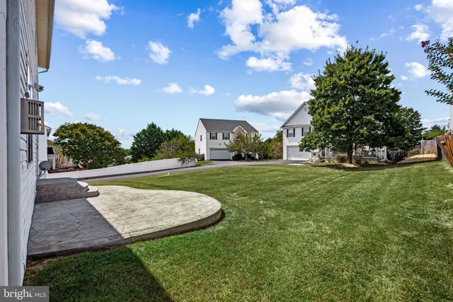 a view of a house with a big yard plants and large tree