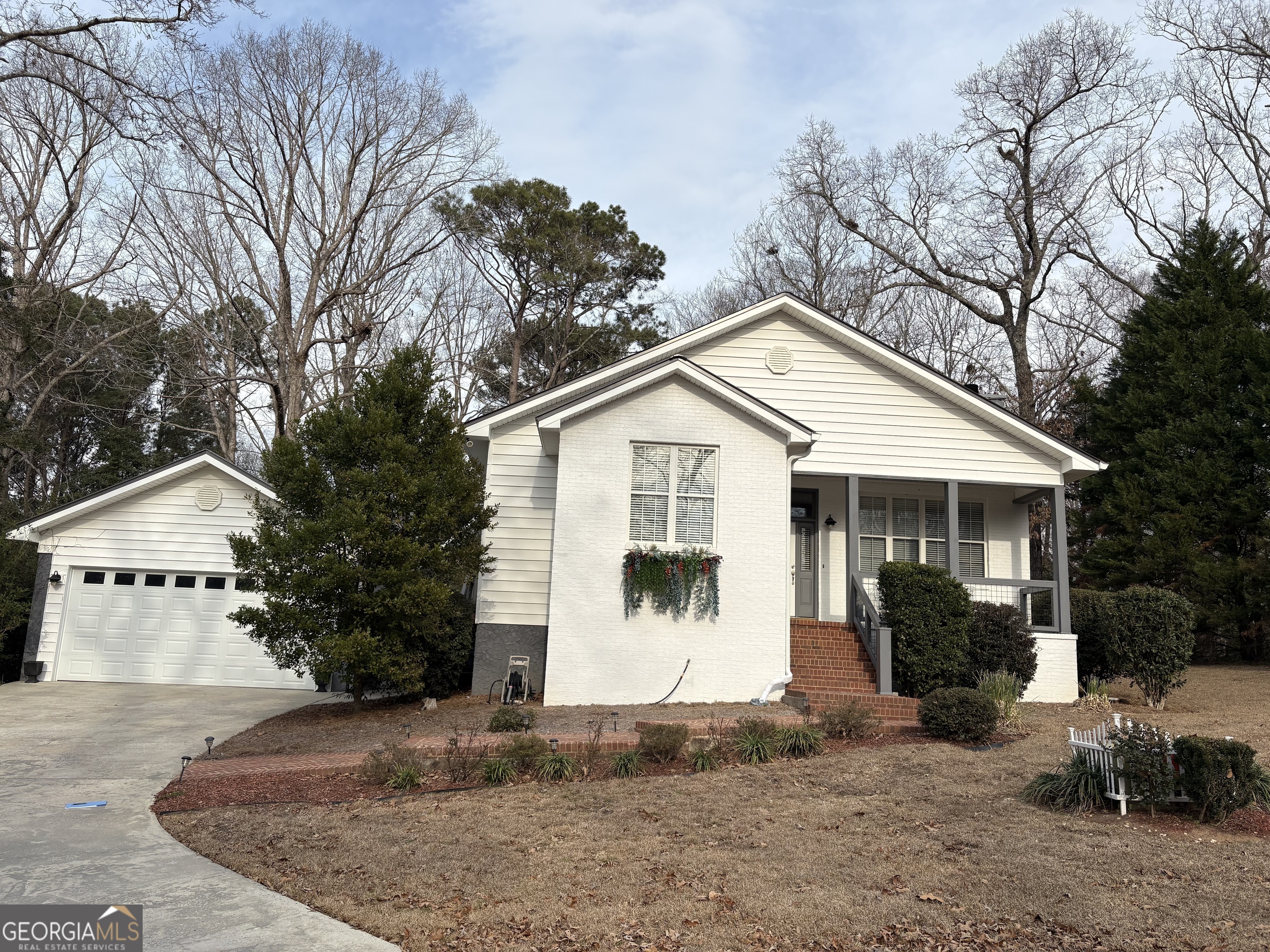 a view of a white house with a small yard and large trees